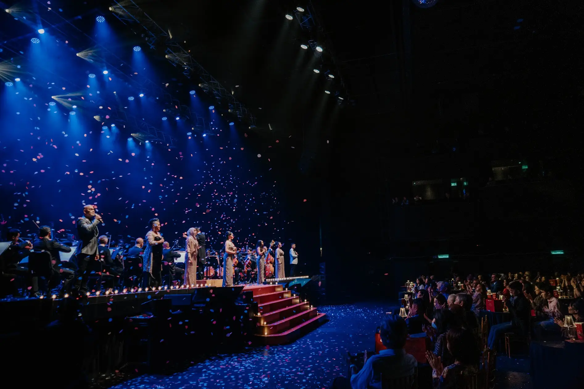 The stage from the side, red steps leading up to it, the audience in silhouette in the foreground.